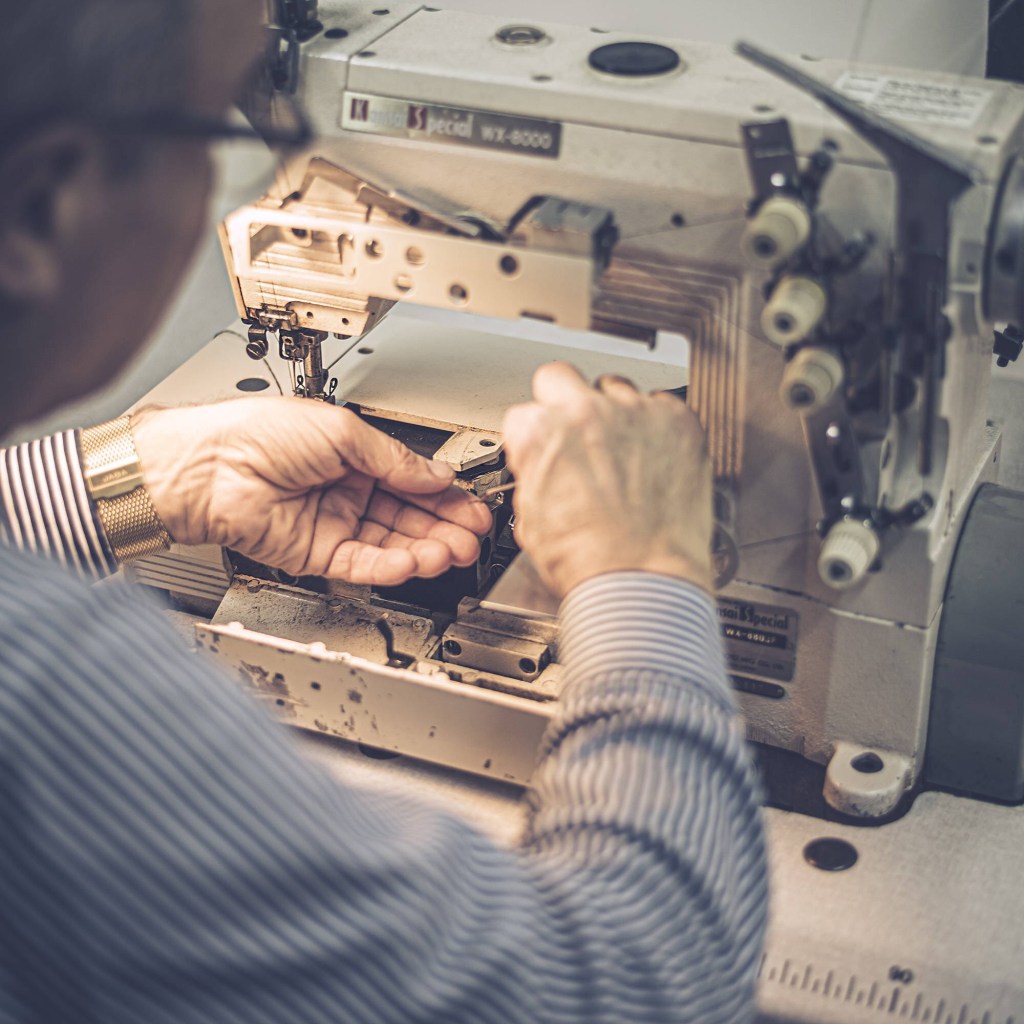 Alt=‘’Homme cousant avec une machine à coudre ‘’